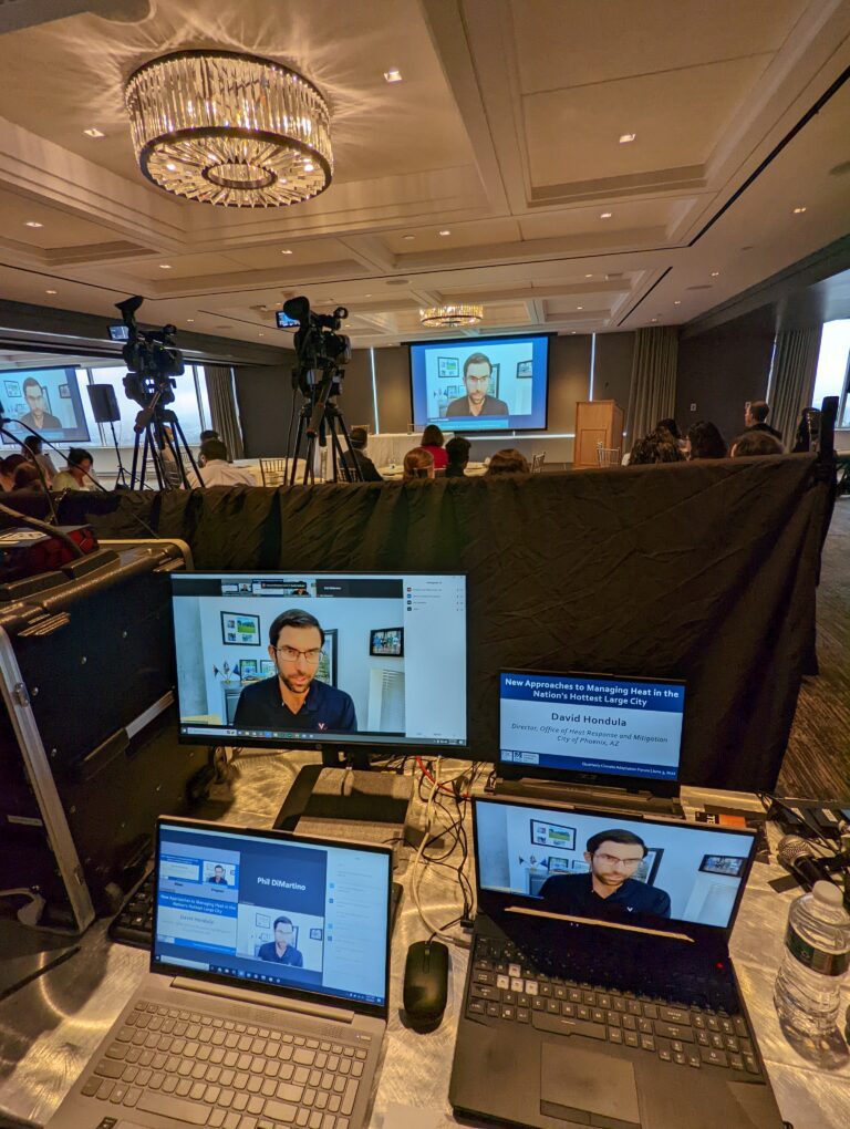 Man on computer screens presenting remotely during hybrid event