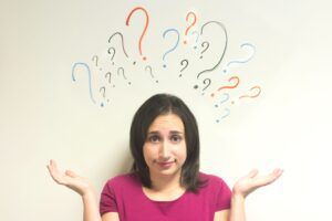 Woman shrugs shoulder with questions marks drawn above her head.