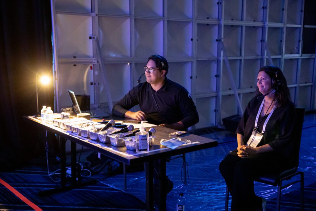 Two people sitting at a production table with mics