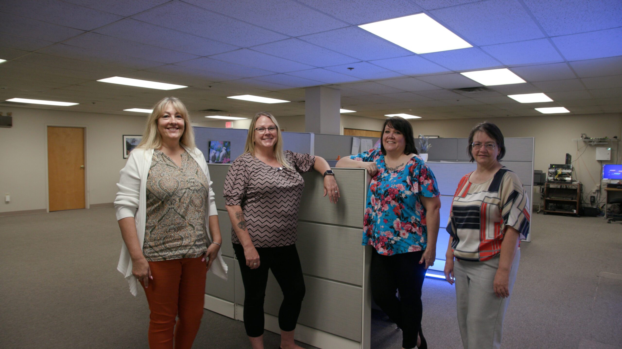 Four women posing for camera in office space