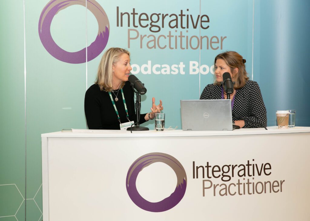 two women sitting behind podcast set creating event content