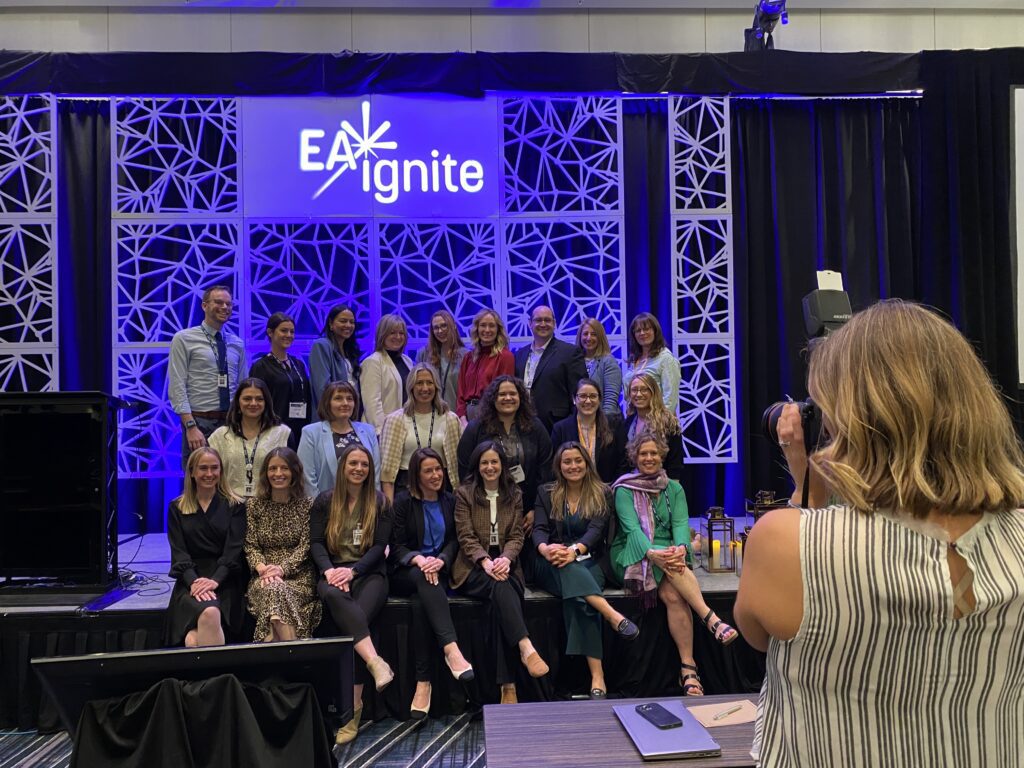 Woman taking team photo of people on stage at an event