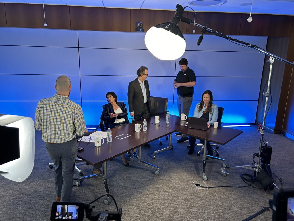 People sitting for a round table discussion with production equipment