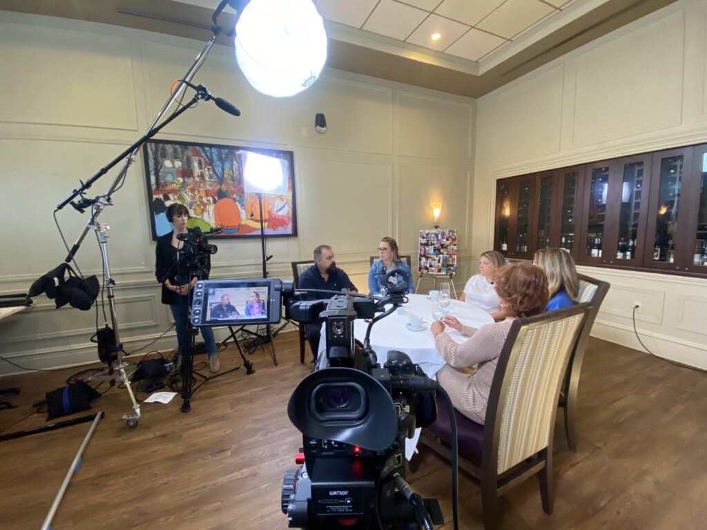 People sitting for a round table discussion with production equipment