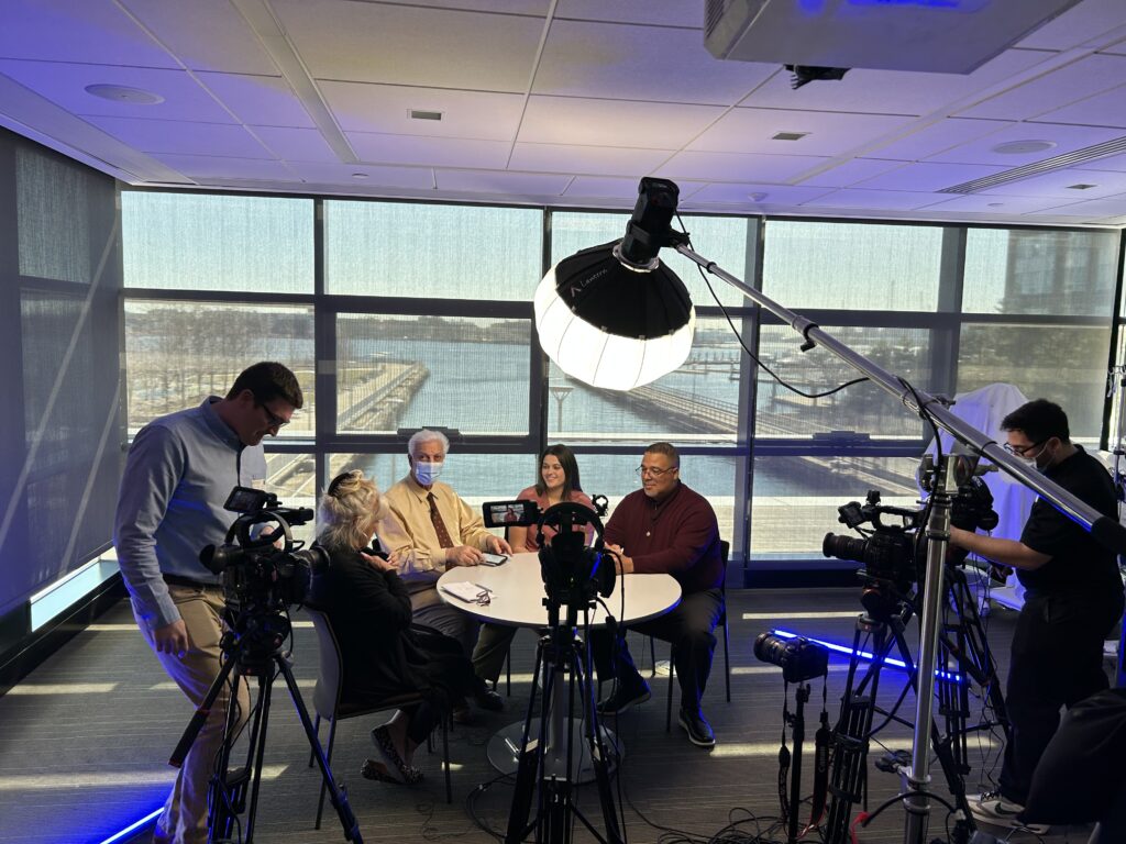 People sitting for a round table discussion with production equipment