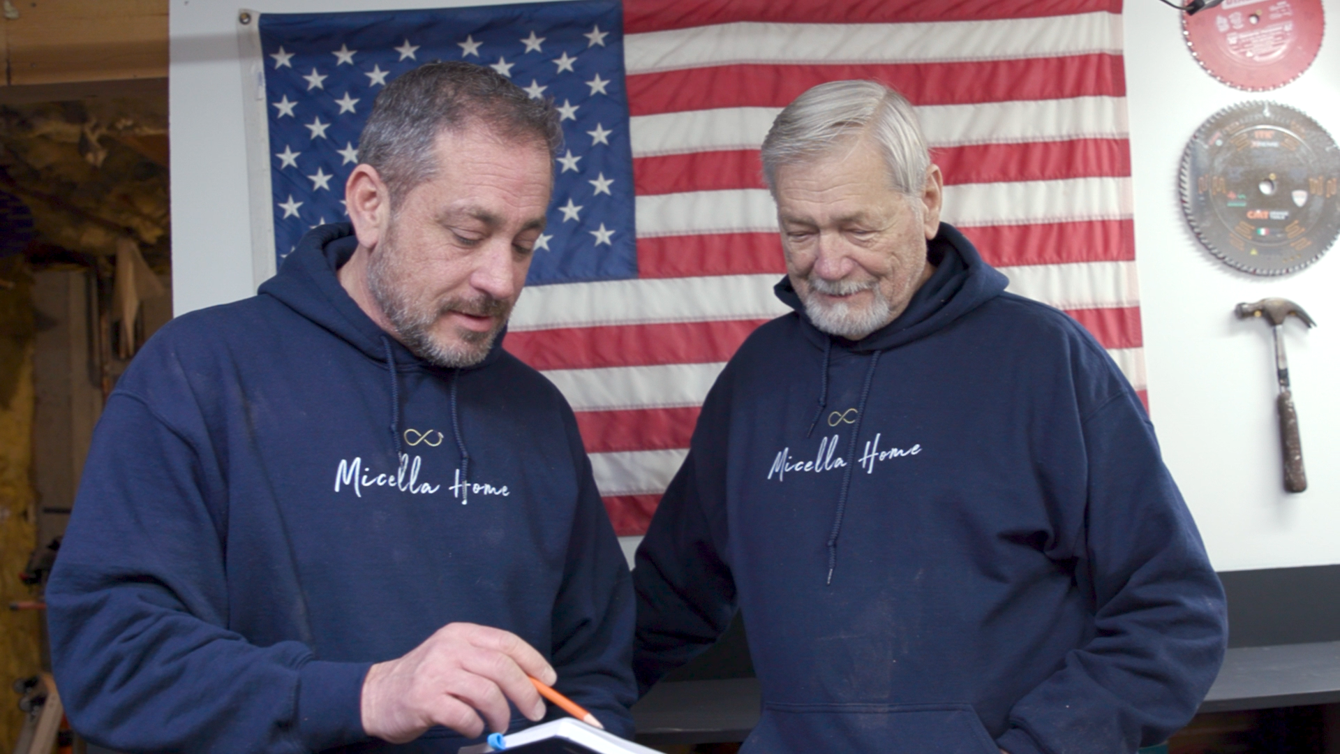 Two men standing over a notebook talking.